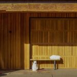 Custom wooden garage door with two cats resting in front